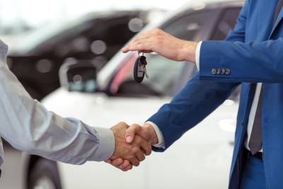 Deux hommes se serrant la main pour conclure la vente d'un véhicule