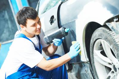 Mécanicien réparant la carrosserie d'un véhicule utilitaire