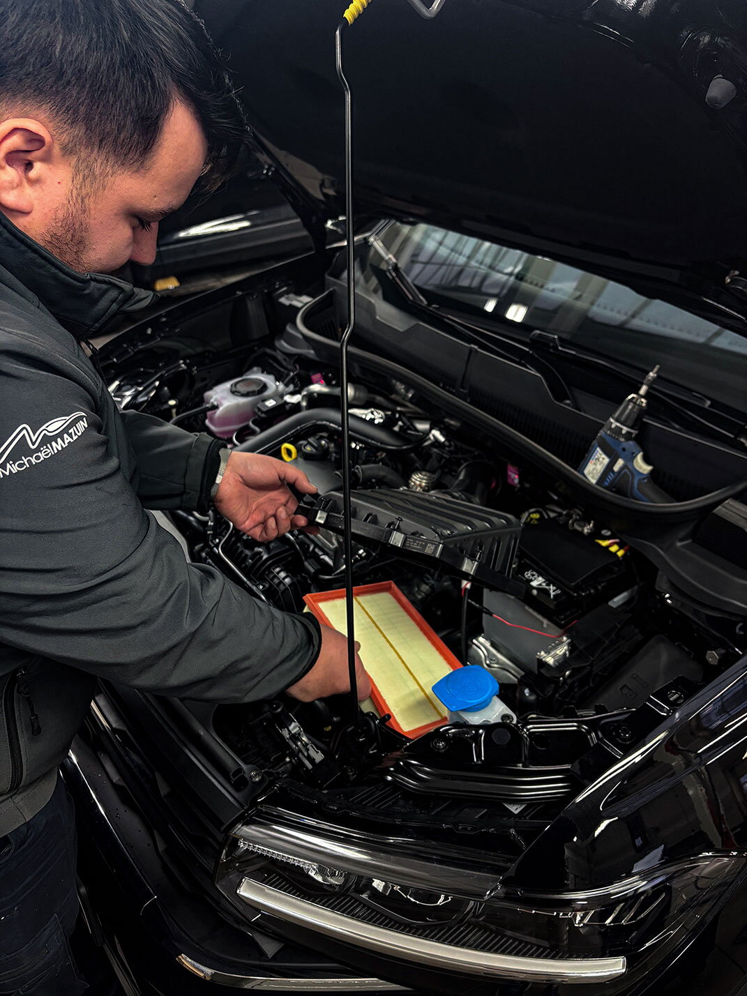 Mécanicien du Garage Mazuin remplaçant un filtre à air lors d’un entretien automobile
